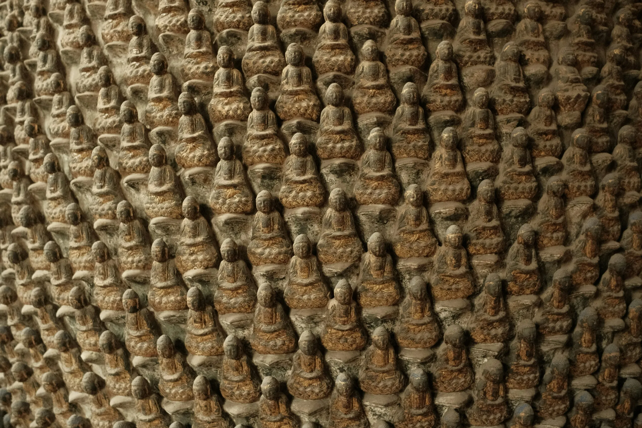 A wall of hundreds of small carved stone figures in rows
