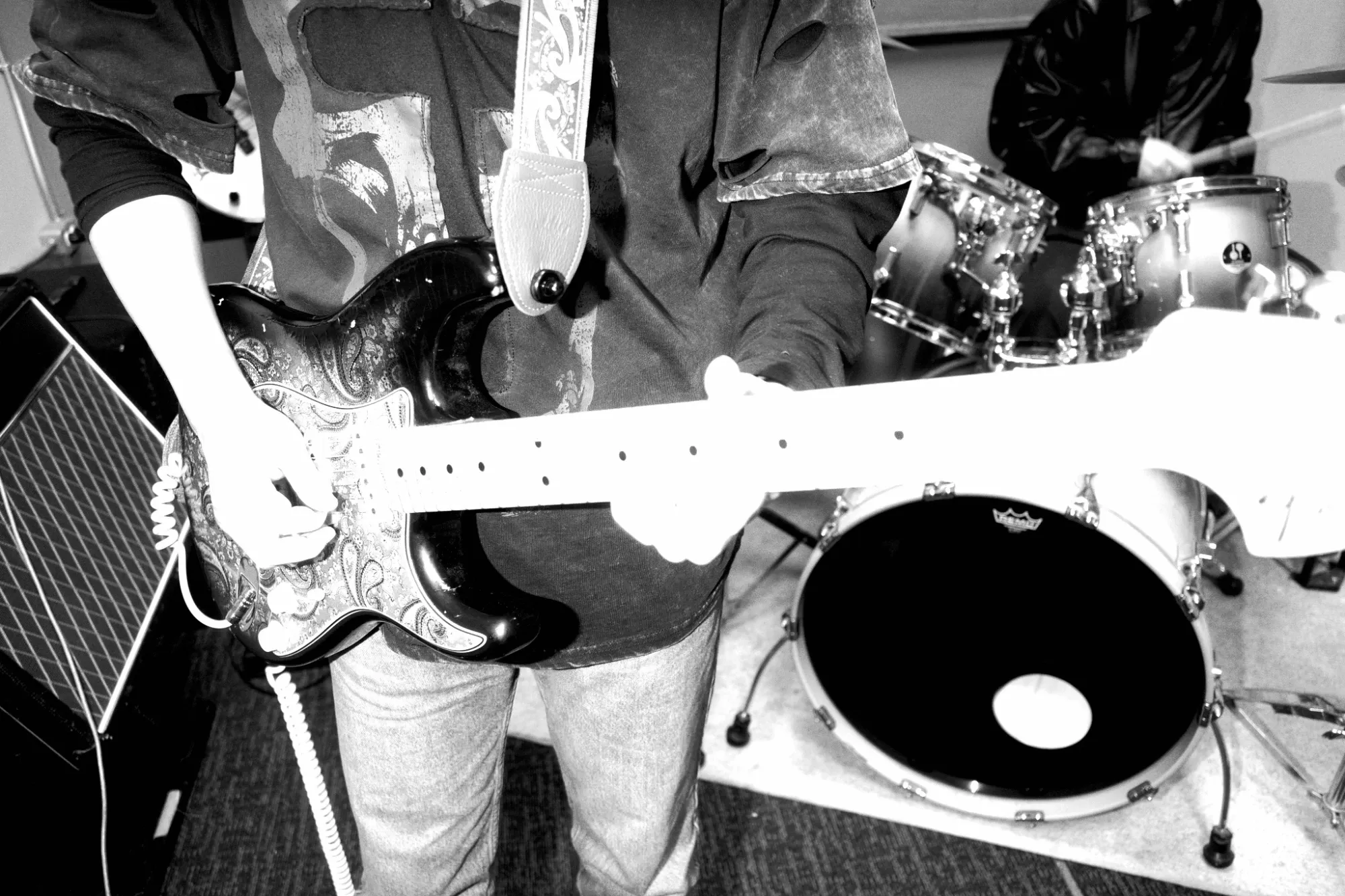 Close-up of a guitarist's paisley electric guitar with the drum kit behind