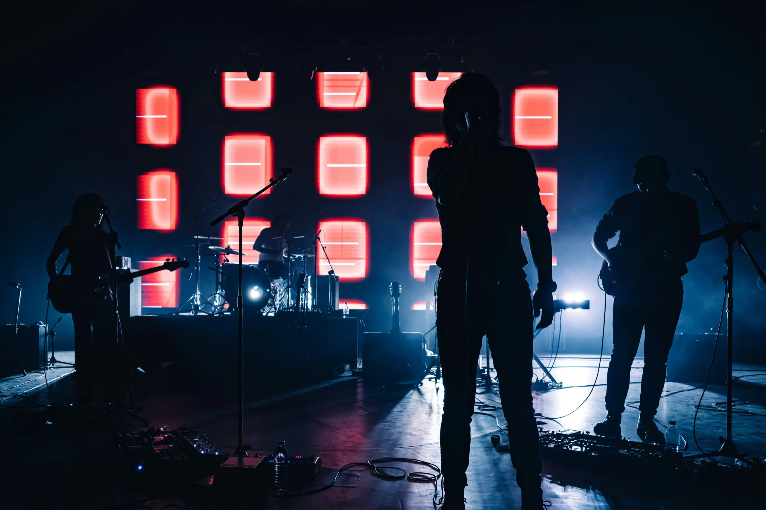 A band in silhouette in front of a wall of glowing red squares