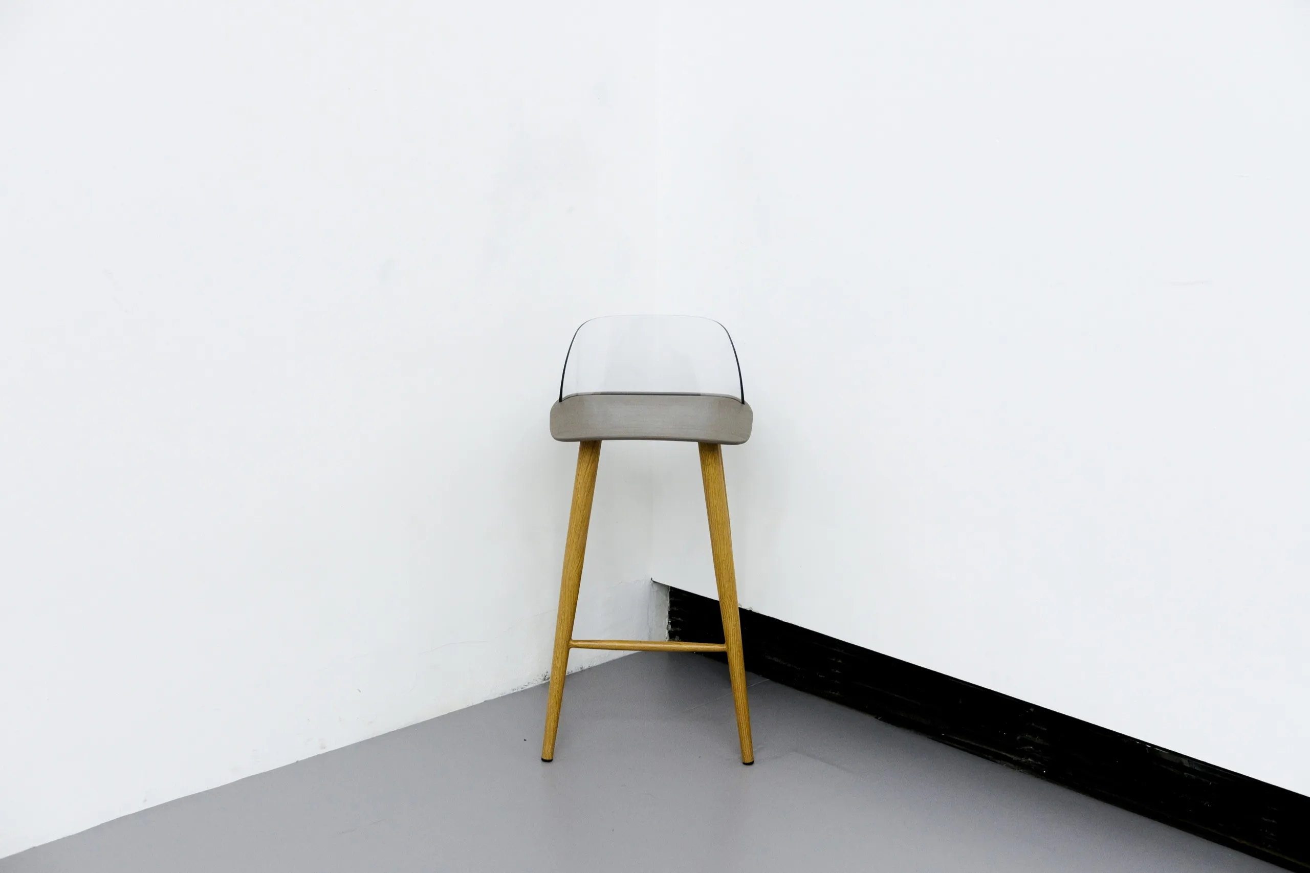 A single bar stool in the corner of a white room