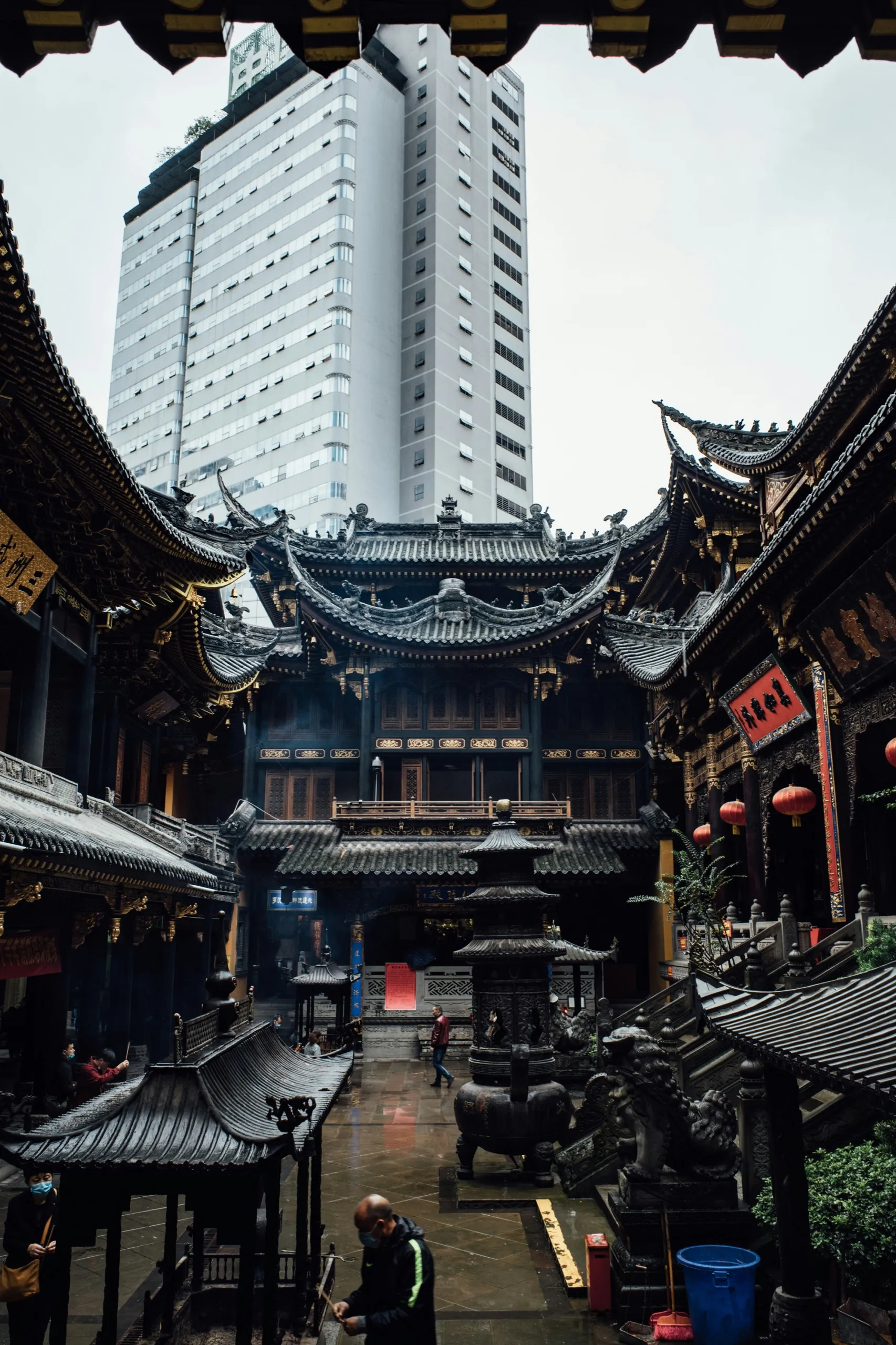 A traditional temple courtyard with a white high-rise tower rising behind it